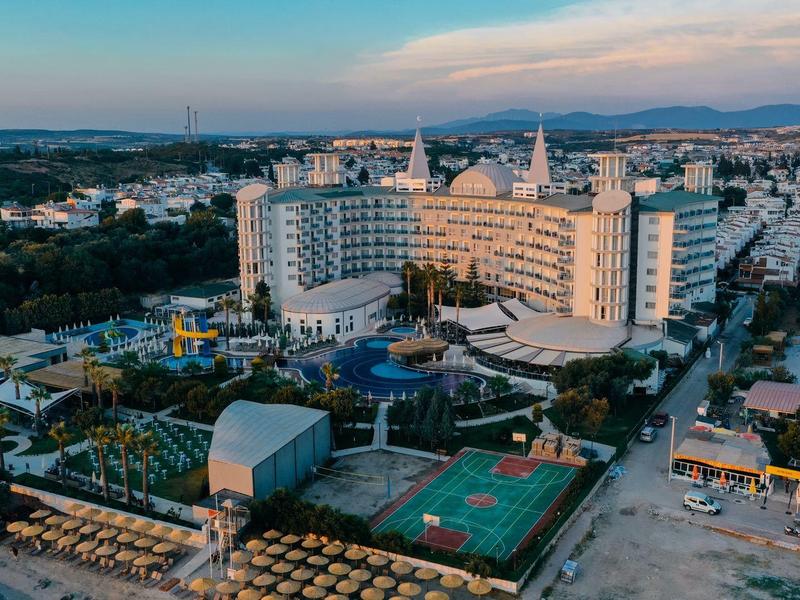 Widok z powietrza na hotel z basenami, strefami relaksu i boisko sportowe w pobliżu wybrzeża.