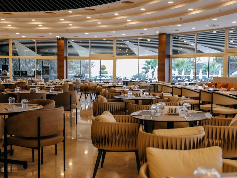 Przestronna restauracja hotelowa z dużymi oknami i wygodnymi miejscami do siedzenia.