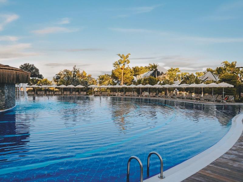 Duży basen na zewnątrz z drewnianym tarasem i jasnym niebem.