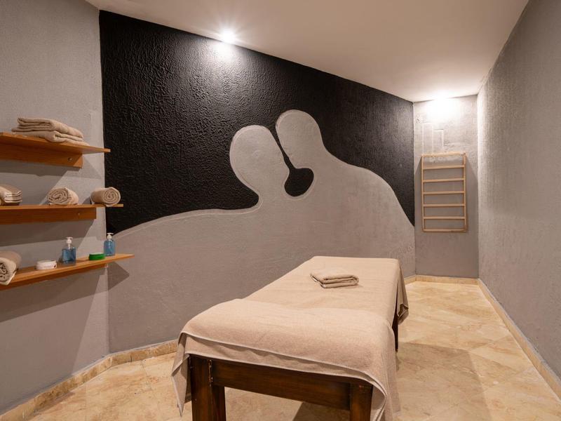 Relaksujący pokój spa z łóżkiem do masażu, szare ściany i minimalistyczne dekoracje.