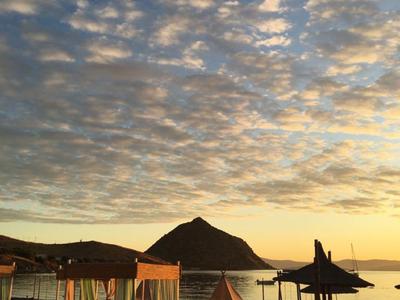 Beach with lounge chairs and umbrellas at sunset with mountain in the background.