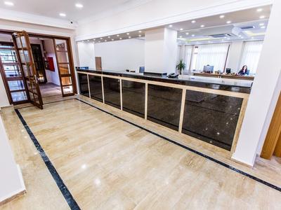 Moderní recepce s dlouhým černým pultem a světlou mramorovou podlahou.