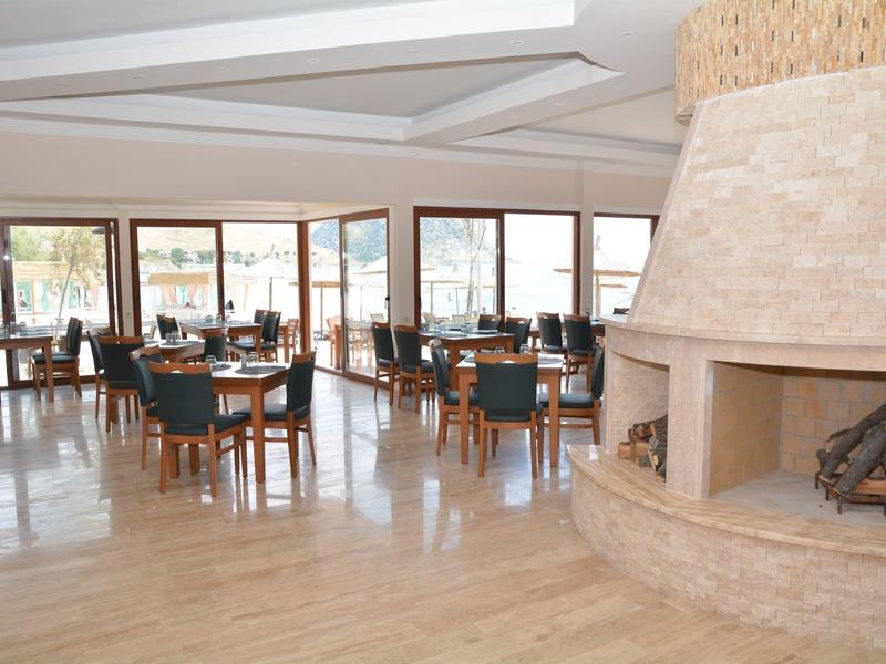 Světle restaurace s moderním dřevěným nábytkem a velkým kamenným krbem v hotelu.