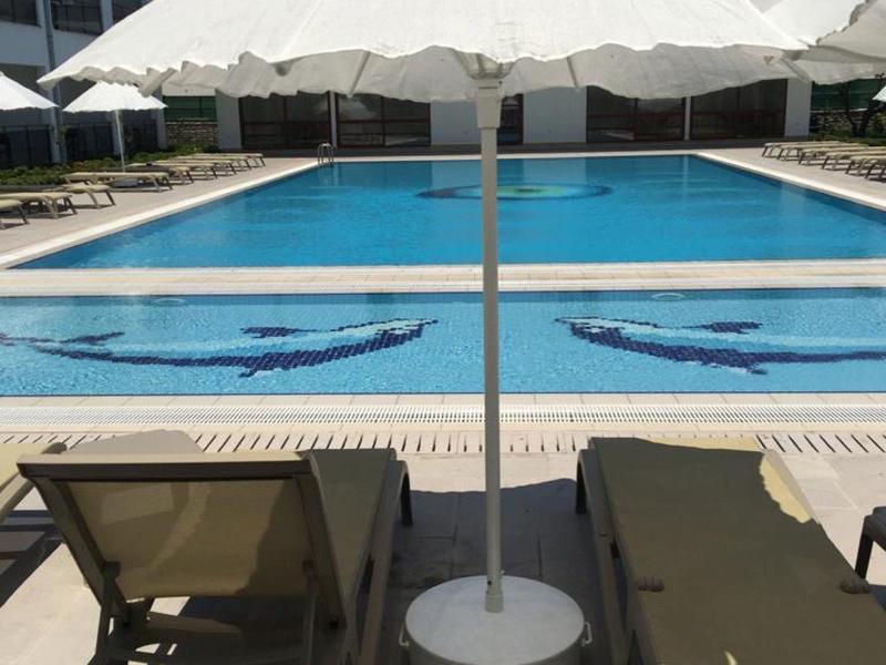 Dvě lehátka a slunečník vedle hotelového bazénu.