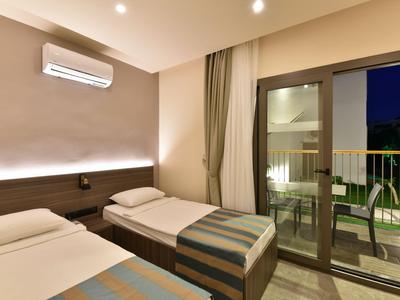 Nowoczesny pokój hotelowy z dwoma pojedynczymi łóżkami i balkonem z miejscami do siedzenia w nocy.