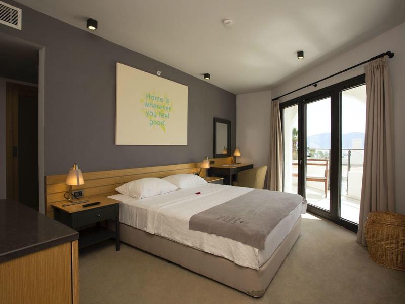 Camera d'hotel accogliente con letto matrimoniale, scrivania, finestra con vista sul balcone.