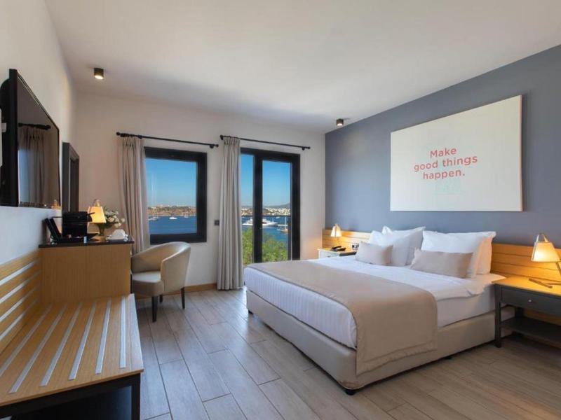 Camera d'hotel moderna con letto matrimoniale, vista mare e scrivania vicino alla finestra