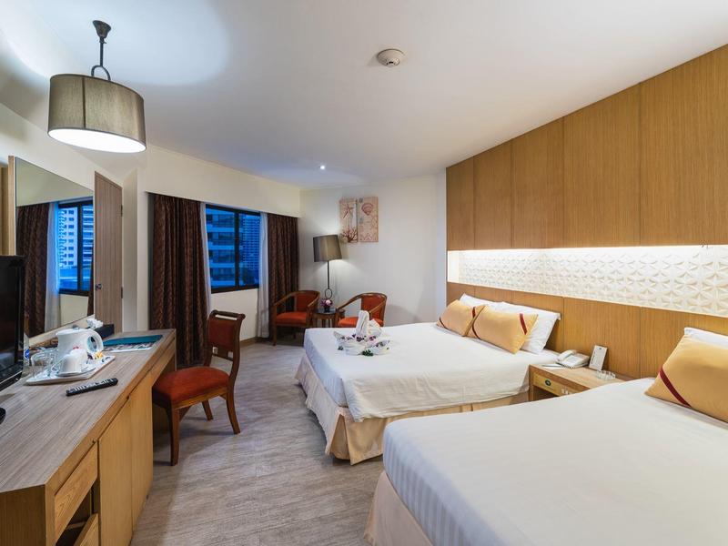 Modernes Hotelzimmer mit zwei Queensize-Betten, Holzmöbeln und warmem, einladendem Licht.