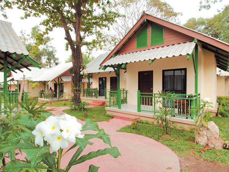 Small bungalows with white walls, green accents, and a well-kept garden with white flowers.