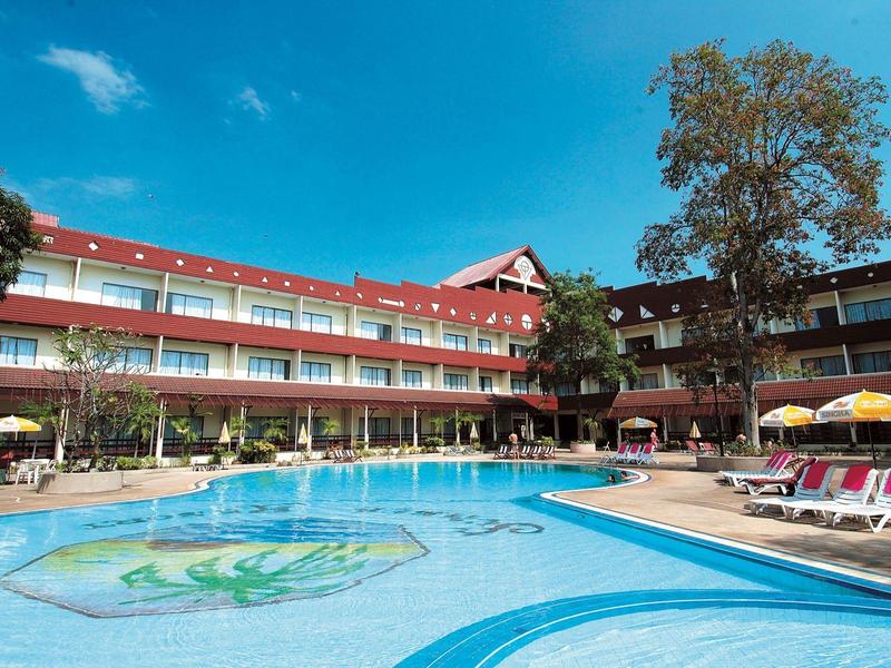 Hotel with large outdoor pool, lounge chairs, and clear blue sky