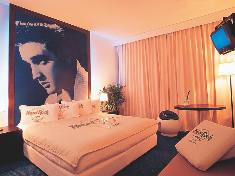 Gemütliches Zimmer mit Doppelbett, Elvis-Poster, Sofakissen, Stehlampe und Fernseher an der Wand.