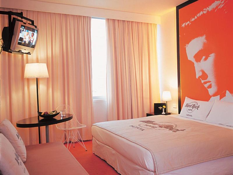 Ein helles Schlafzimmer mit großem Bett, roten Teppich und einem Bild von Elvis Presley an der Wand.