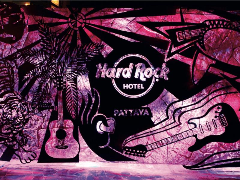 Bunte Wandkunst mit Gitarren, Palmen und Hard Rock Hotel Pattaya Schriftzug in Pink und Schwarz.