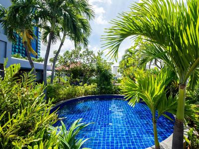 Blauer Pool umgeben von üppigen grünen Pflanzen und Palmen in einer tropischen Hotelanlage.