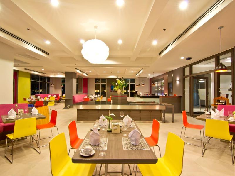 Moderner Gastraum mit bunten Stühlen, gedeckten Tischen und sanfter Beleuchtung.