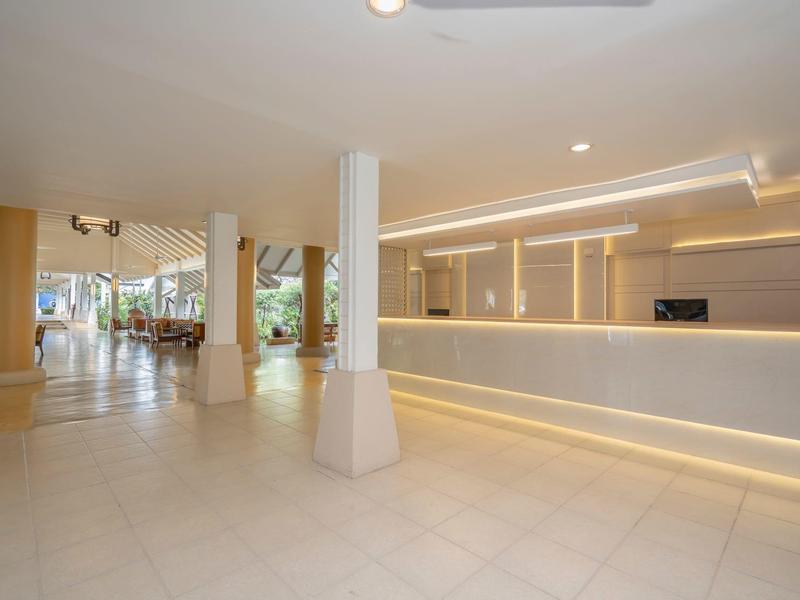 Heller, großer Empfangsbereich mit langem Tresen, weißen Säulen und Stuhlgruppen im Hintergrund.
