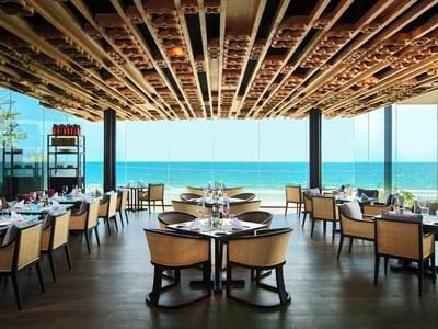 Elegantes Restaurant mit Blick auf das Meer und Holzkonstruktion an der Decke.