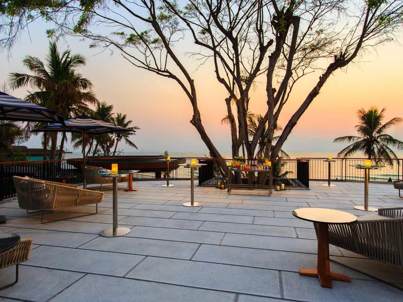 Terrace with seating and trees at sunset by the sea