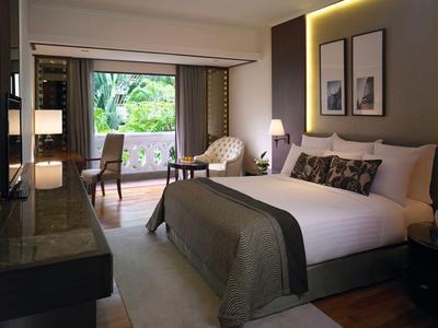 Modern eingerichtetes Hotelzimmer mit großem Bett, Sitzbereich und Balkon mit Blick ins Grüne.