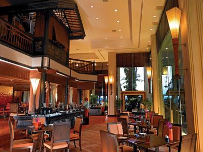 Großes, elegantes Restaurant mit Holzmöbeln, hohen Decken und warmem Licht in modernem Stil.