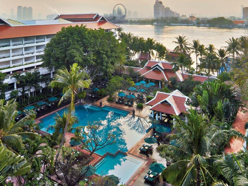 Hotelanlage mit Swimmingpool und Palmen nahe eines Flusses und einer Stadtlandschaft