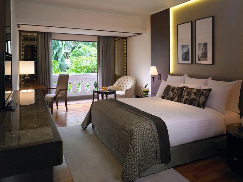 Modern eingerichtetes Hotelzimmer mit großem Bett, Sitzbereich und Balkon mit Blick ins Grüne.