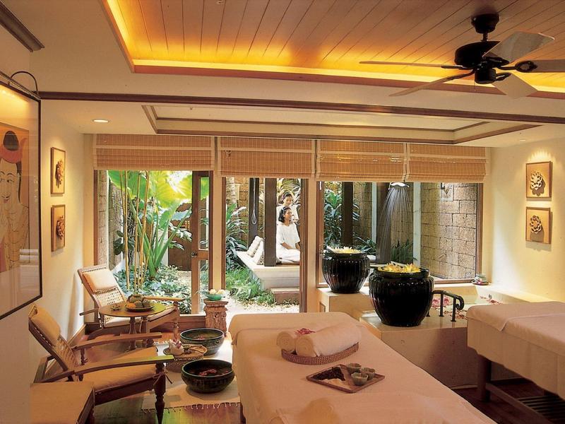 Gemütlicher, stilvoll eingerichteter Spa-Raum mit Massageliegen, Pflanzen und warmem Licht.