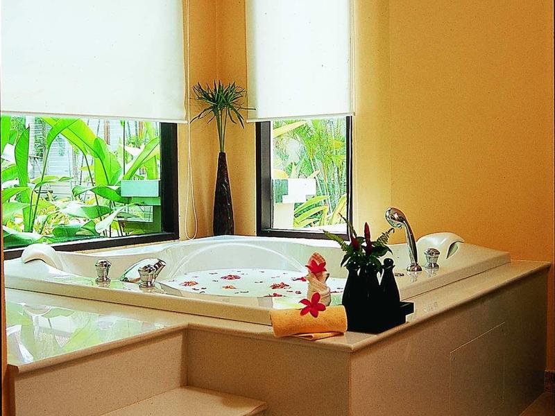 Moderner Whirlpool mit Stufen, orangen Wänden und großen Fenstern mit weißen Rollos.