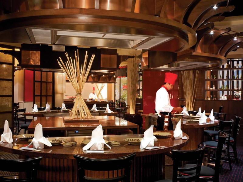 Gemütliches Restaurant mit dunklem Holz, runden Tischen und aufwendig gefalteten Servietten.