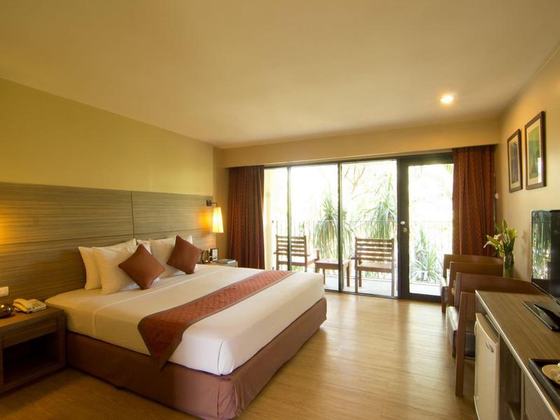 Modernes Hotelzimmer mit großem Doppelbett, Holzboden, Balkon und warmem Licht.