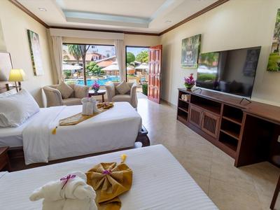 Modernes Hotelzimmer mit zwei Betten, Sofa, großem Fernseher und Balkon mit Blick ins Grüne.