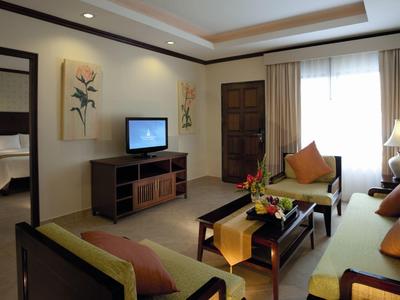 Wohnzimmer mit Sofa, TV, Couchtisch, Lampen und Vorhängen in warmen Farbtönen und weichem Licht.