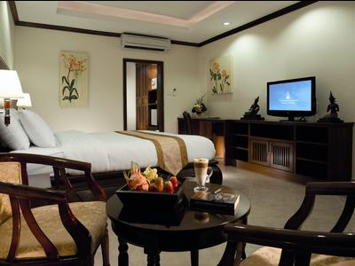 Gemütliches Hotelzimmer mit Doppelbett, Holzmöbeln, TV und dekorativen Wandbildern.