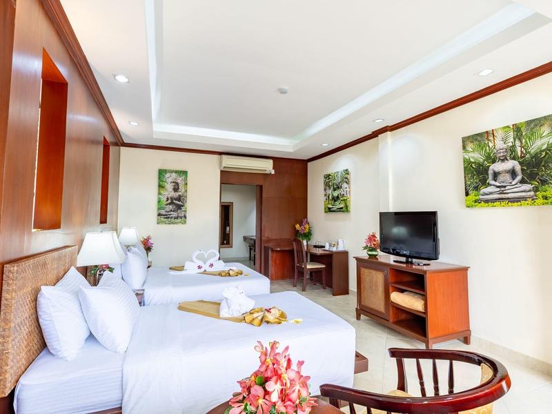 Großes Zimmer mit zwei Betten, Holzmöbeln, TV und heller Wanddekoration.