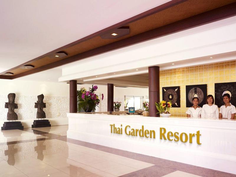 Moderne Hotelhalle mit weißem Empfangstresen und fünf schwarzen Statuen auf weißem Boden.