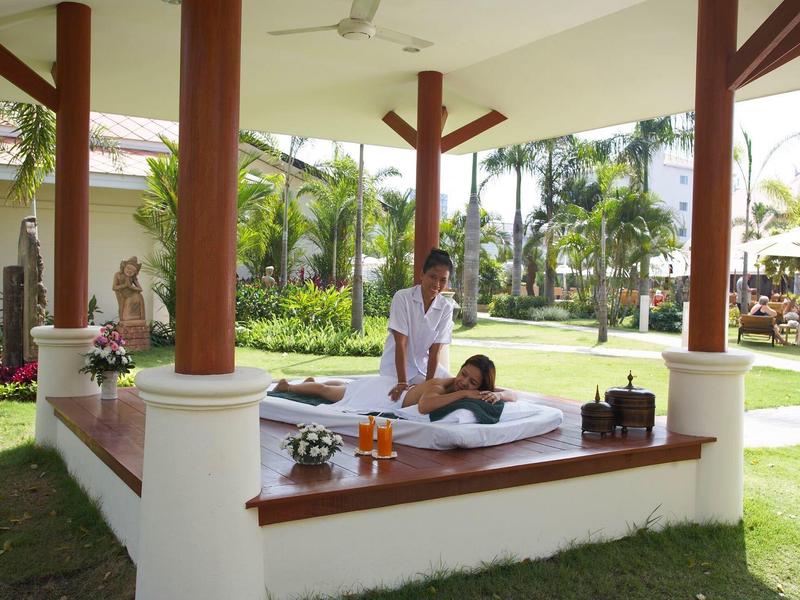 Offener Massagebereich im Freien mit Holzboden, Säulen und entspannender Gartenanlage.