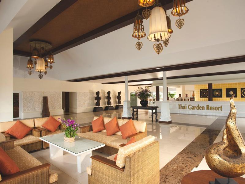 Moderner Hotel-Lobbybereich mit bequemen Sofas, orangefarbenen Kissen und Dekorationen in warmen Farben.