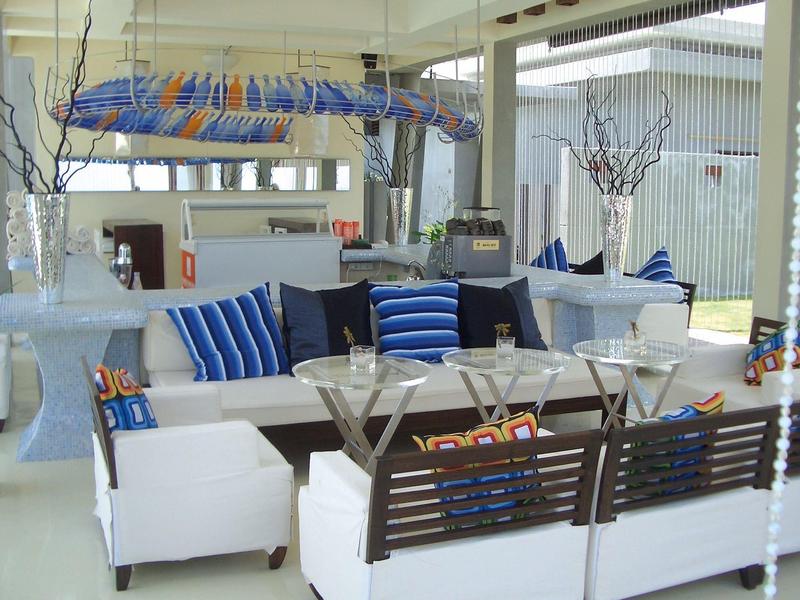 Moderner, lichtdurchfluteter Wohnbereich mit weißen Möbeln und blauen Akzenten, großem Fensterfront.