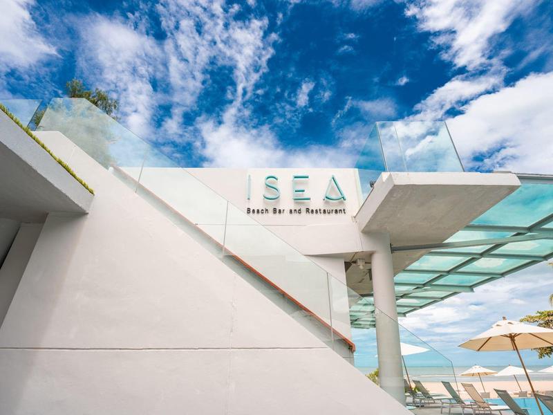 Modernes Café mit weißer Architektur und Glasdach unter blauem Himmel mit Wolken.