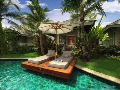Two lounge chairs with umbrella on wooden platform in pool at tropical hotel.
