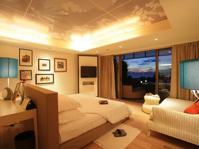 Cozy hotel room with large windows, beds, and warm ambient lighting.