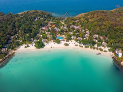 Aerial view of a tropical beach with turquoise water and hotel facilities in the forest