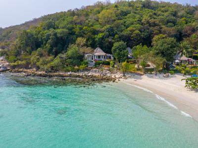 Strand mit klarem türkisfarbenem Wasser und grünen Hügeln im Hintergrund