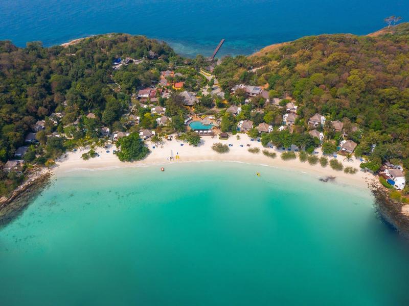 Aerial view of a tropical beach with turquoise water and hotel facilities in the forest