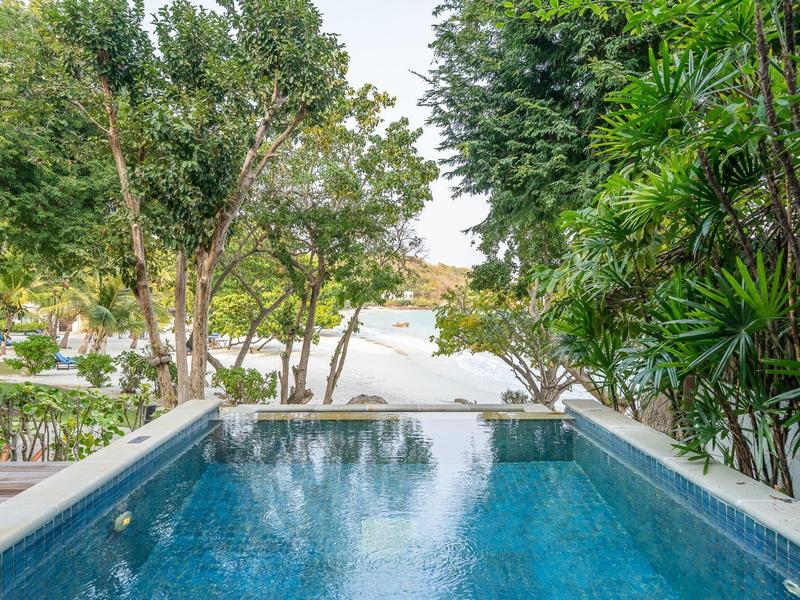 Private pool overlooking a tropical garden and beach in the background.
