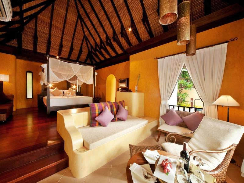 Cozy hotel room area with wooden roof, canopy bed, and comfortable seating.