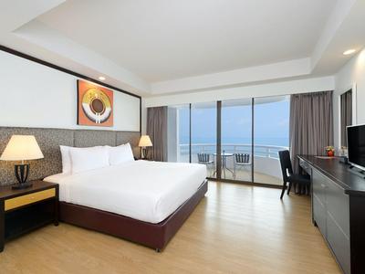 Camera d'hotel moderna con letto grande, scrivania e balcone con vista mare.