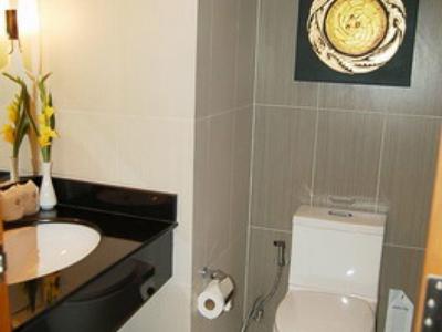 Kleines Badezimmer mit weißer Toilette, schwarzem Waschbecken, Wäschekorb und dekorativer Uhr an der Wand.