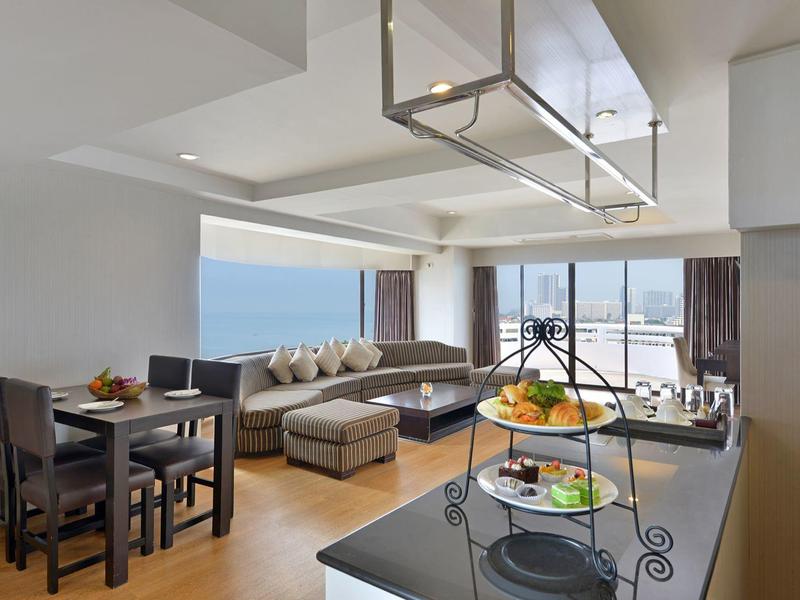 Moderner Wohnraum mit Holzboden, Essbereich, Ecksofa, großen Fenstern und Meerblick.