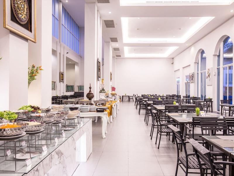 Großer heller Speisesaal mit vielen Tischen und Buffet auf der linken Seite.